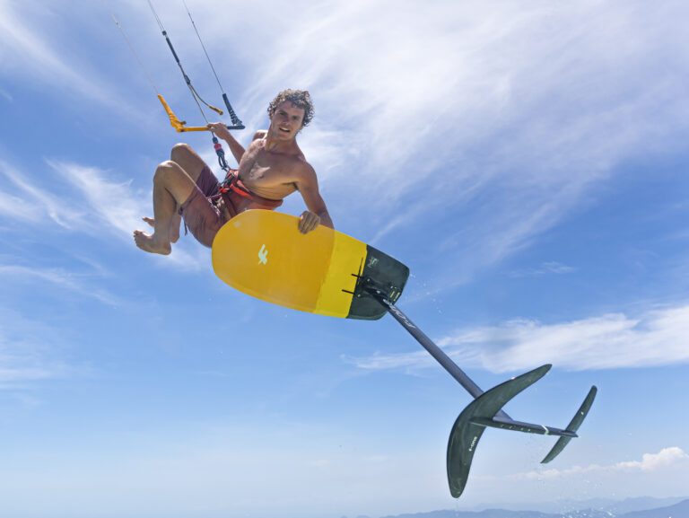Un homme saute en kite foil, mettant bien en vue sa planche et son foil